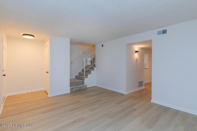 empty room with light hardwood / wood-style floors and a textured ceiling