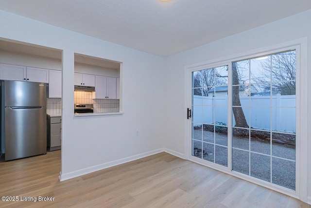 kitchen featuring stainless steel refrigerator, backsplash, white cabinets, range, and light hardwood / wood-style floors