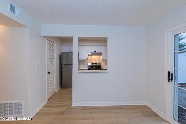 kitchen with white cabinetry, appliances with stainless steel finishes, decorative backsplash, and light hardwood / wood-style flooring