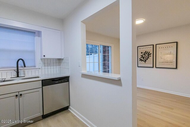 kitchen featuring dishwasher, sink, gray cabinetry, backsplash, and light wood-type flooring