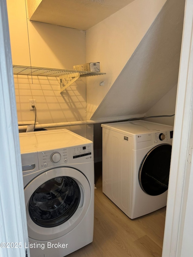 clothes washing area featuring washing machine and clothes dryer and light hardwood / wood-style flooring