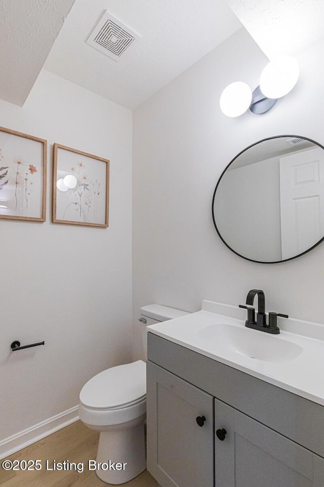 bathroom with vanity, toilet, and wood-type flooring