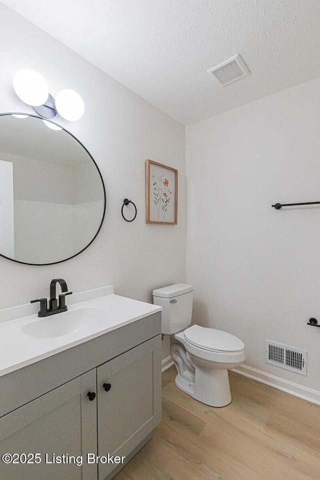 bathroom with hardwood / wood-style flooring, vanity, a textured ceiling, and toilet