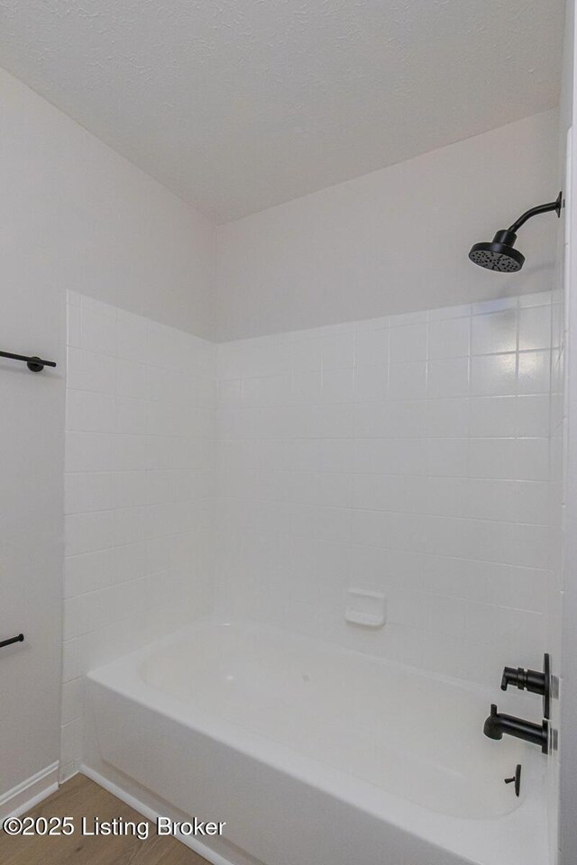 bathroom with hardwood / wood-style floors and washtub / shower combination