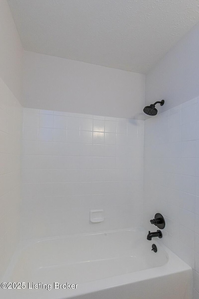 bathroom with tiled shower / bath and a textured ceiling