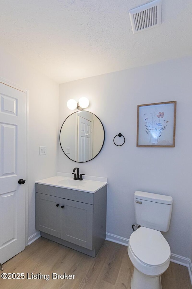 bathroom featuring hardwood / wood-style flooring, vanity, a textured ceiling, and toilet