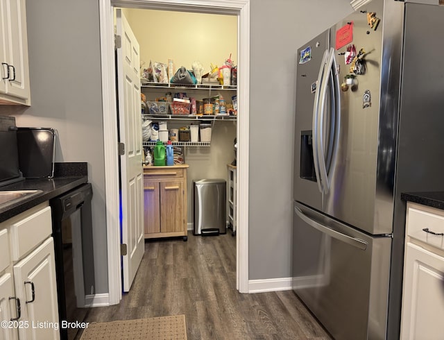 kitchen with dark hardwood / wood-style flooring, white cabinetry, stainless steel fridge, and black dishwasher