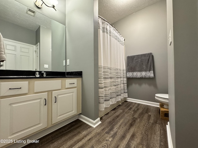 bathroom with curtained shower, wood-type flooring, vanity, toilet, and a textured ceiling