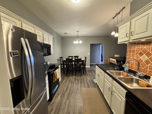 kitchen with sink, tasteful backsplash, dark hardwood / wood-style flooring, pendant lighting, and black appliances