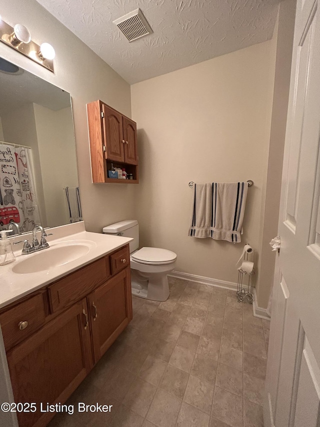 bathroom featuring vanity, a textured ceiling, and toilet