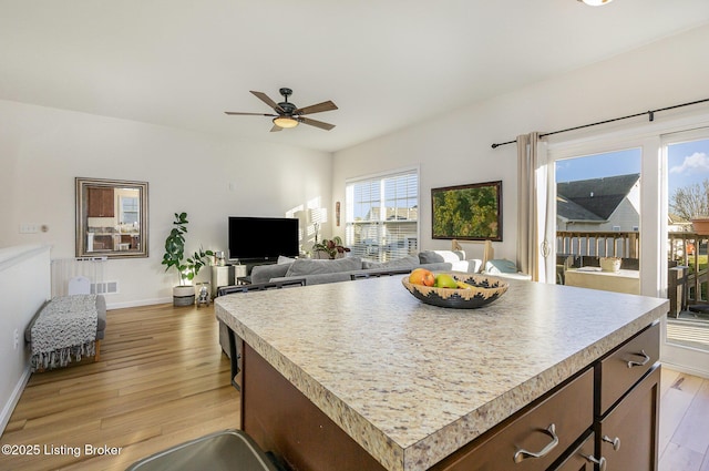 kitchen with ceiling fan, a center island, and light hardwood / wood-style floors