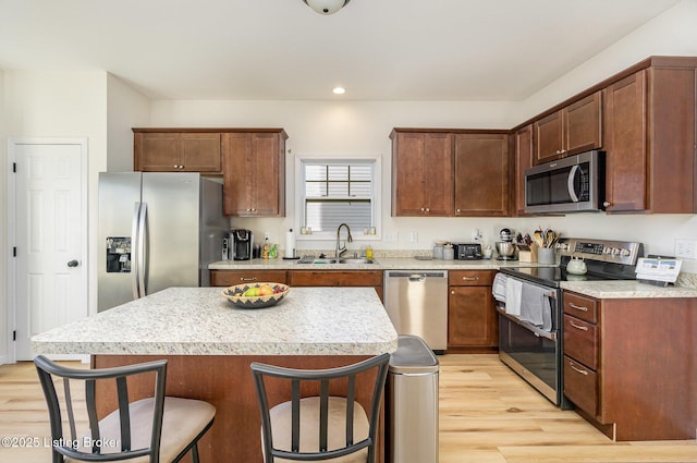 kitchen featuring sink, a breakfast bar area, a kitchen island, stainless steel appliances, and light hardwood / wood-style floors