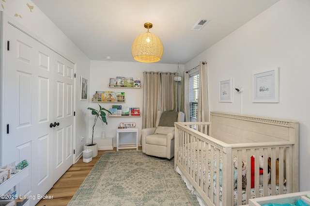 bedroom featuring wood-type flooring, a closet, and a nursery area