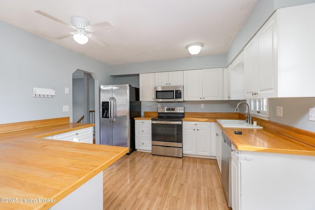 kitchen featuring sink, light hardwood / wood-style flooring, appliances with stainless steel finishes, kitchen peninsula, and white cabinets