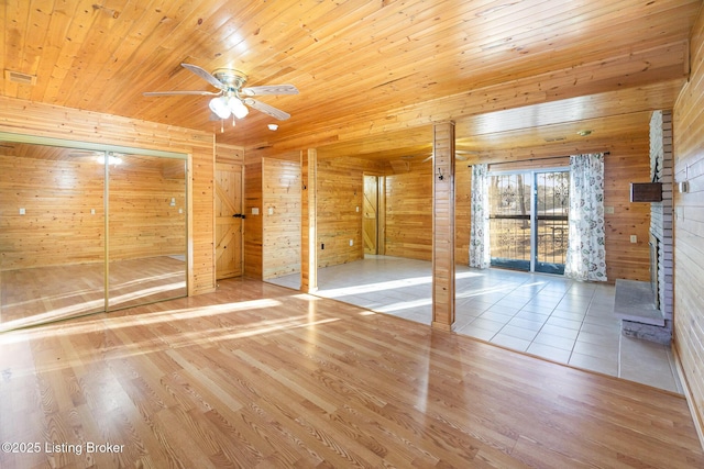 interior space featuring ceiling fan, hardwood / wood-style floors, wooden walls, a brick fireplace, and wooden ceiling