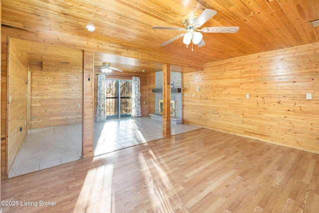 spare room featuring ceiling fan, wood walls, light hardwood / wood-style flooring, and wooden ceiling