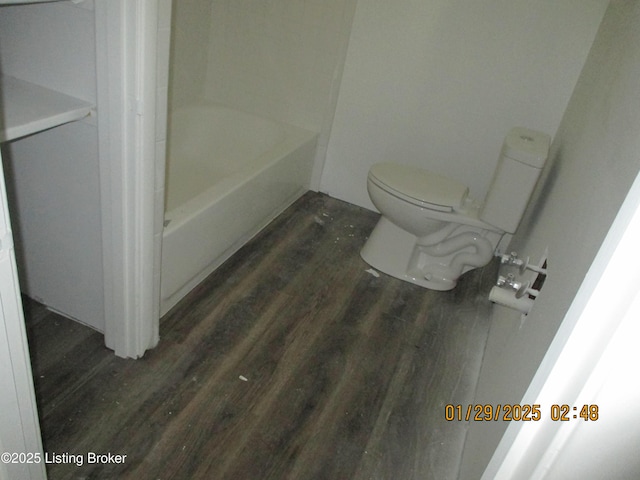 bathroom featuring radiator, wood-type flooring, toilet, and a tub to relax in