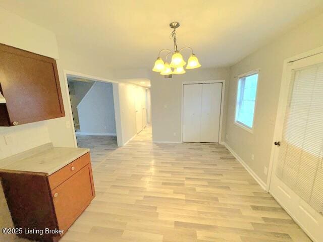 unfurnished dining area with an inviting chandelier and light hardwood / wood-style floors