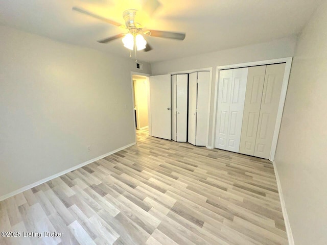 unfurnished bedroom with ceiling fan, two closets, and light wood-type flooring