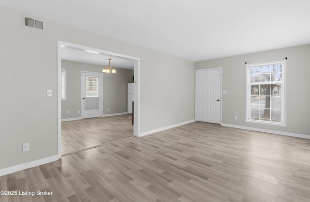 unfurnished living room with visible vents, baseboards, a notable chandelier, and light wood-style flooring