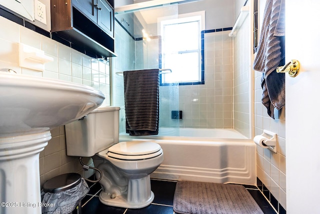 bathroom with tile walls, tile patterned flooring, tiled shower / bath combo, and toilet