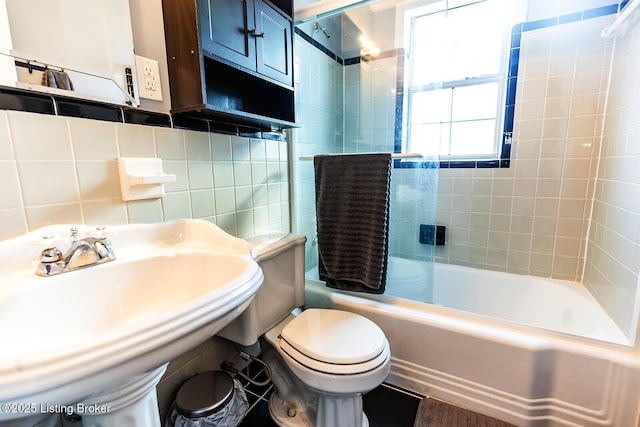 full bathroom featuring sink, tile walls, tiled shower / bath combo, decorative backsplash, and toilet