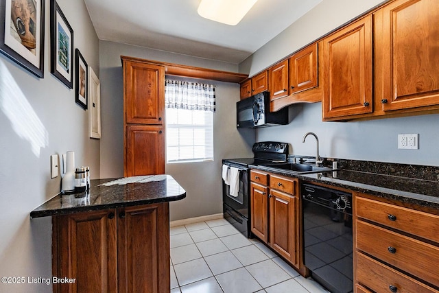 kitchen featuring sink, dark stone countertops, light tile patterned floors, and black appliances