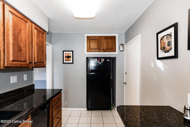 kitchen featuring light tile patterned floors, dark stone counters, and black appliances