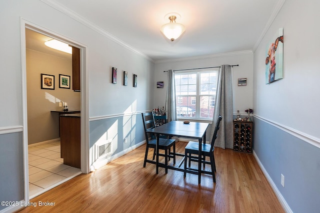 dining area with ornamental molding and light hardwood / wood-style flooring