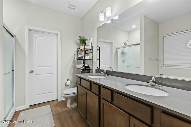 bathroom featuring hardwood / wood-style flooring, vanity, a shower with door, and toilet