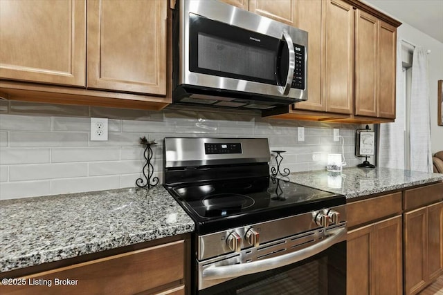 kitchen with tasteful backsplash, light stone countertops, and appliances with stainless steel finishes