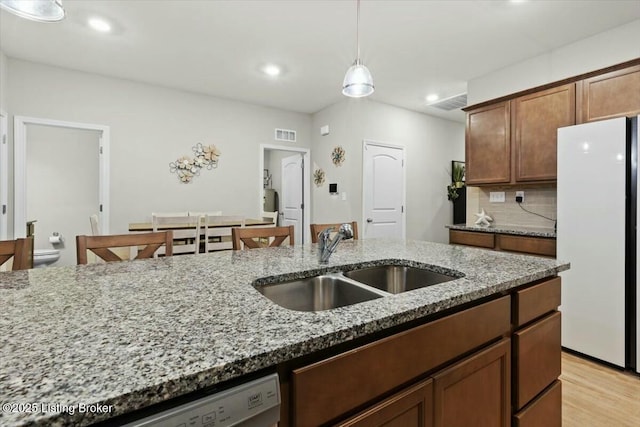 kitchen with pendant lighting, sink, white appliances, backsplash, and light stone counters