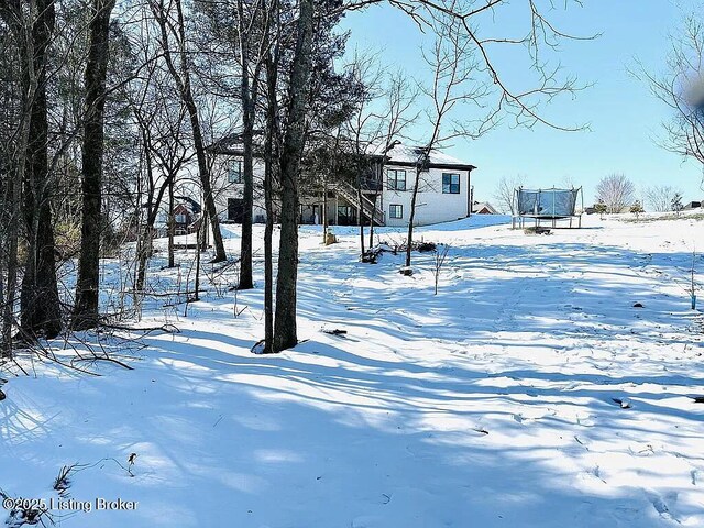 yard layered in snow featuring a trampoline