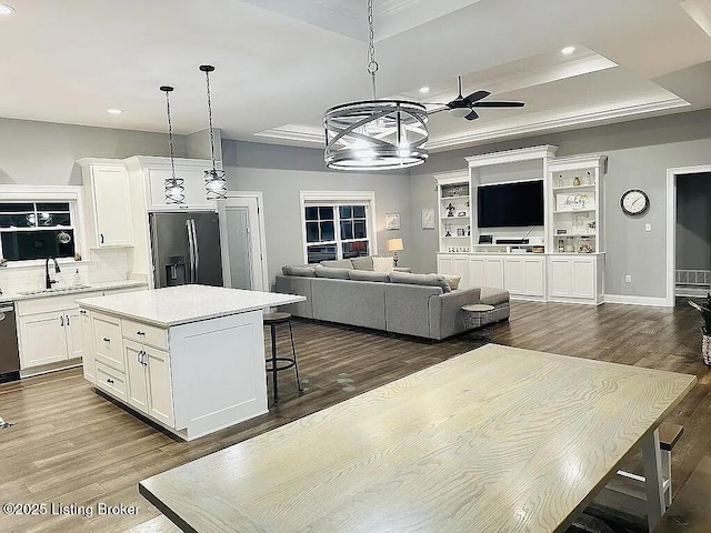 kitchen featuring a tray ceiling, stainless steel fridge, a center island, and white cabinets