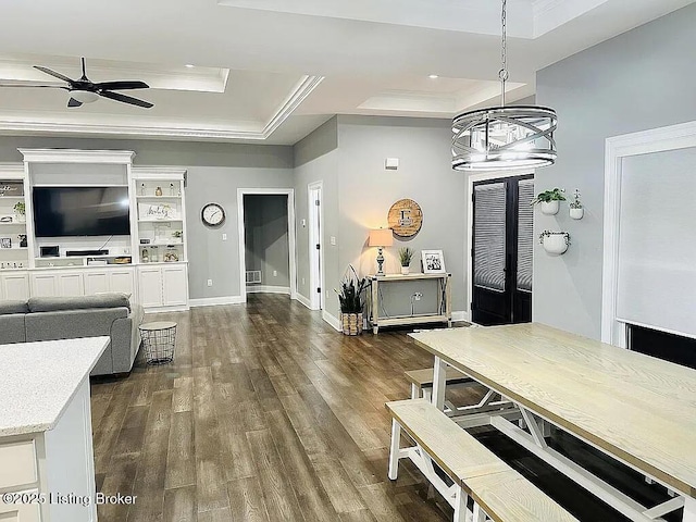 dining area with dark hardwood / wood-style flooring, crown molding, ceiling fan with notable chandelier, and a raised ceiling