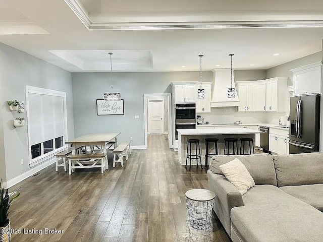 living room featuring dark hardwood / wood-style floors, a tray ceiling, and sink