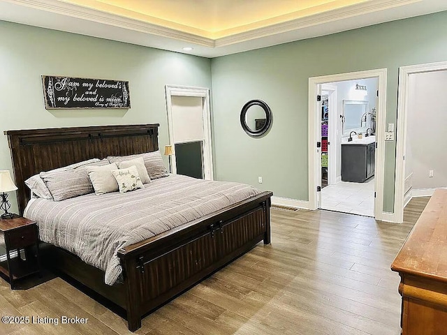 bedroom with crown molding, sink, and light hardwood / wood-style flooring