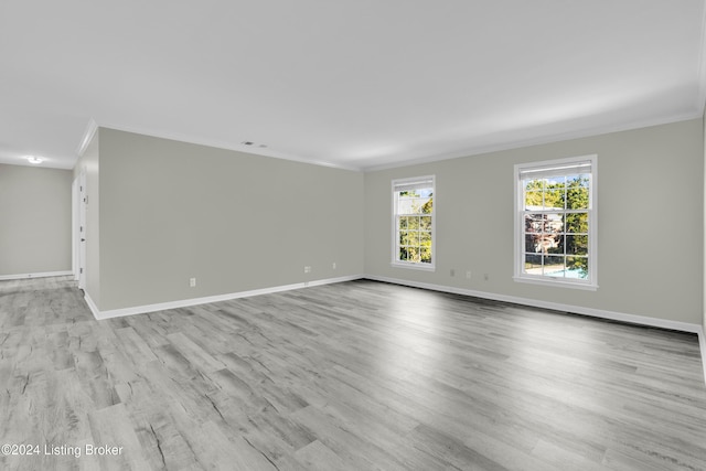 empty room with crown molding and light wood-type flooring