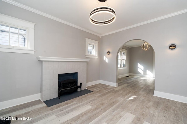 unfurnished living room with crown molding, a brick fireplace, and light wood-type flooring