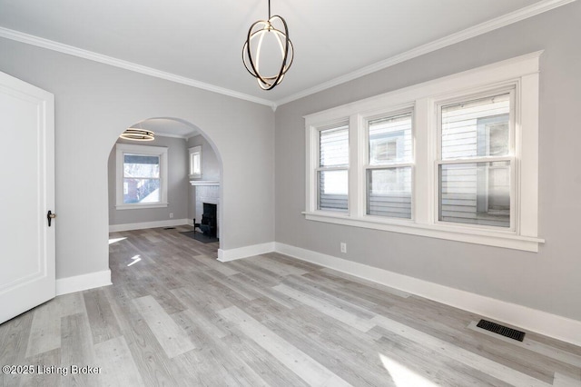 unfurnished living room featuring an inviting chandelier, crown molding, and light hardwood / wood-style flooring