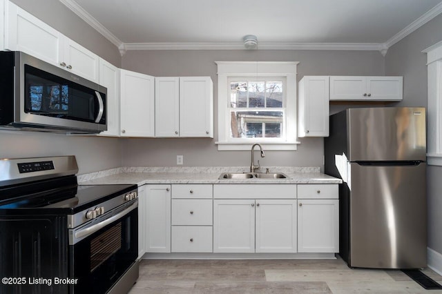 kitchen featuring sink, light hardwood / wood-style flooring, ornamental molding, appliances with stainless steel finishes, and white cabinets