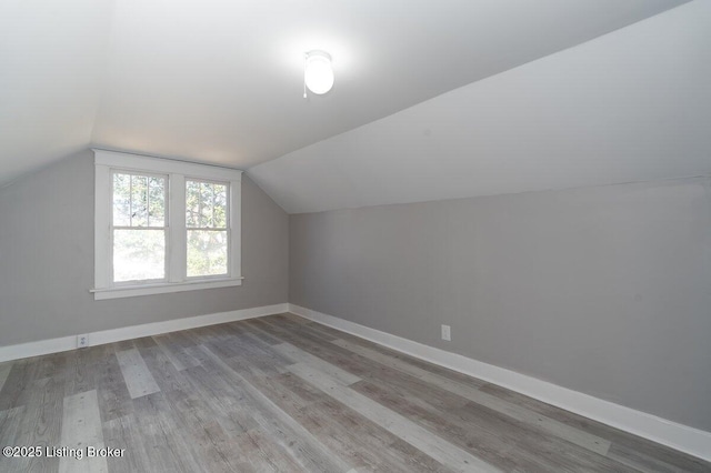 additional living space featuring vaulted ceiling and hardwood / wood-style floors