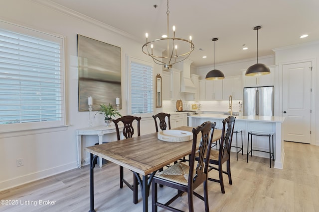 dining area with an inviting chandelier, sink, ornamental molding, and light wood-type flooring