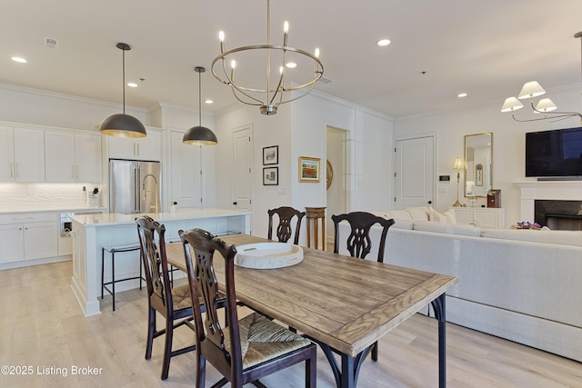 dining area featuring an inviting chandelier, ornamental molding, and light wood-type flooring