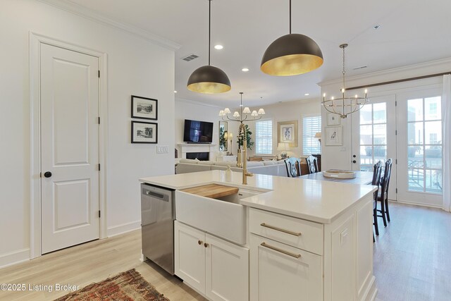 kitchen with an inviting chandelier, dishwasher, pendant lighting, a kitchen island with sink, and white cabinets