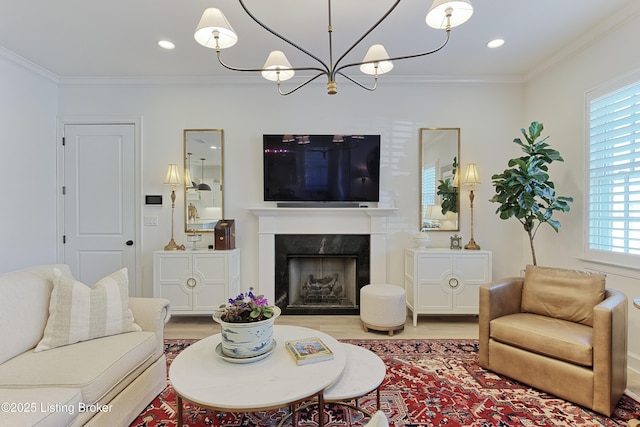 living room with a premium fireplace, crown molding, wood-type flooring, and a chandelier