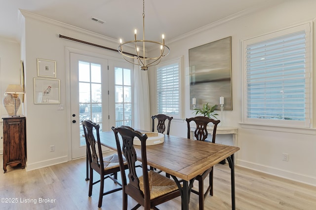 dining space with crown molding, a chandelier, and light hardwood / wood-style flooring