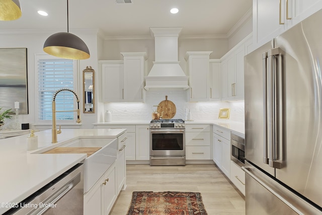 kitchen featuring premium range hood, white cabinetry, ornamental molding, pendant lighting, and stainless steel appliances