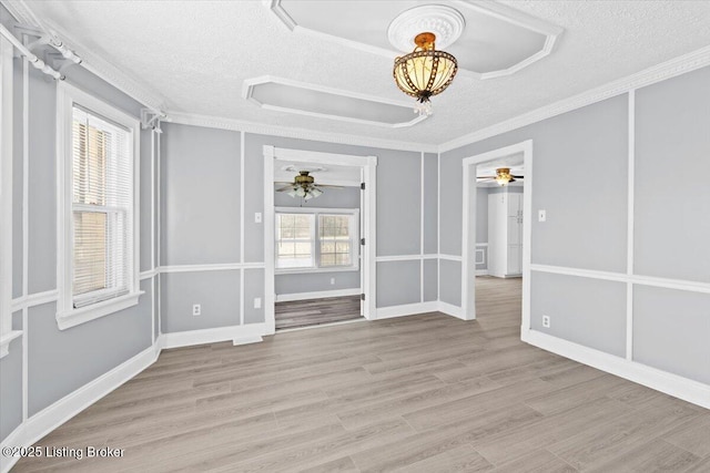 spare room with ceiling fan, light hardwood / wood-style flooring, ornamental molding, and a textured ceiling