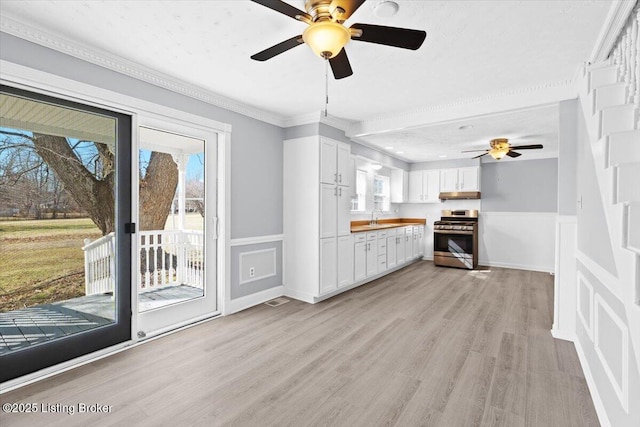 kitchen with butcher block counters, stainless steel range oven, sink, light hardwood / wood-style floors, and white cabinets